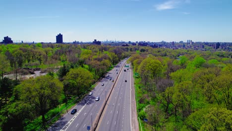 Drone-view-over-I-87-in-the-Bronx,-showcasing-a-clear-road,-green-parks,-and-NYC-skyline