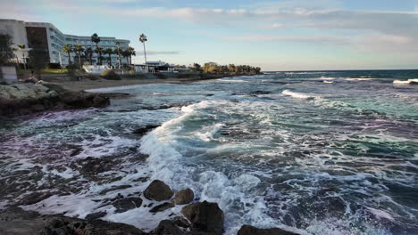 Waves-crashing-on-the-shore-near-a-coastal-hotel