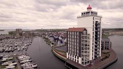 Aerial-of-De-Knar-recreational-port-at-the-Veluwemeer-with-pleasure-boats-and-apartment-building-in-the-shape-of-a-lighthouse