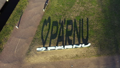 Heart-Shaped-"I-Love-Pärnu"-Sign-Casting-Shadow-on-Grass-in-aerial-top-down-view