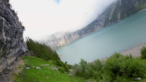 Luftflug-Neben-Einem-Wasserfall-In-Einer-Berglandschaft,-Drohne-Fliegt-Vorwärts-über-Den-Blauen-See---Oeschinensee,-Schweiz