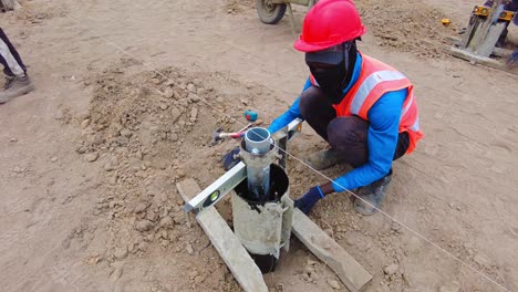 Trabajador-De-La-Construcción-Con-Equipo-De-Seguridad-Operando-Equipos-En-Un-Sitio-Polvoriento-Al-Aire-Libre,-Primer-Plano