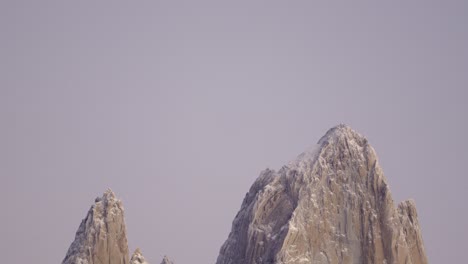 Descending-shot-reveals-the-steep-peak-of-Mount-Fitz-Roy-in-the-morning's-rosy-light-in-Patagonia,-Argentina