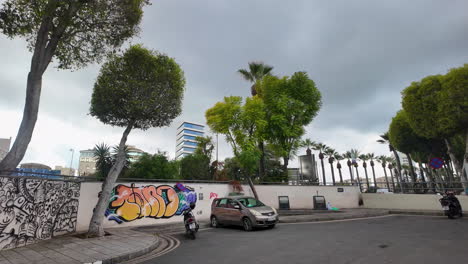 Street-view-in-Nicosia,-Cyprus,-with-a-mural-covered-wall-and-a-mix-of-modern-and-older-buildings