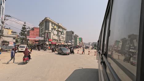 A-view-from-the-window-of-a-bus-on-the-bustling-and-dusty-Ring-Road-of-Kathmandu,-capturing-the-hectic-main-traffic-artery-of-the-city