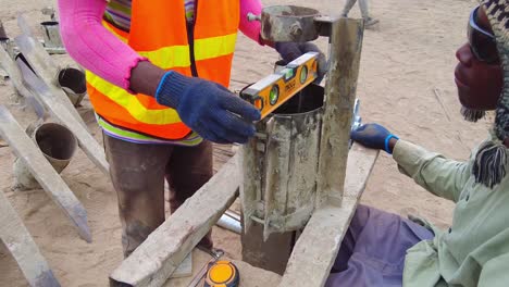 African-technician-worker-checking-level-of-concrete-frame-mould-in-Jambur,-Gambia