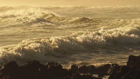 Rough-Sea-Waves-Crashing-On-Rocky-Shoreline-During-Golden-Afternoon---Close-Up-Pan-Shot