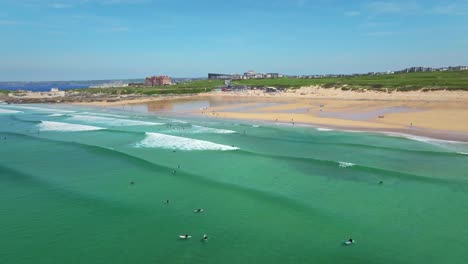 Paisaje-De-Playa-Fistral-Con-Aguas-Turquesas,-Olas-Del-Mar-Y-Surfistas-Disfrutando-Del-Verano-De-Cornualles,-Reino-Unido