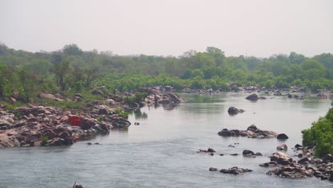 Toma-Panorámica-Del-Río-Betwa-Que-Fluye-A-Través-De-Un-Terreno-Rocoso-En-Las-Orillas-Del-Bosque-Cerca-De-Orchha-En-Madhya-Pradesh,-India