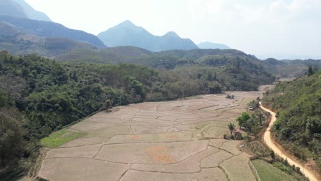 Drone-shot-of-farm-fields-in-the-mountain-town-of-Nong-Khiaw-in-Laos,-Southeast-Asia