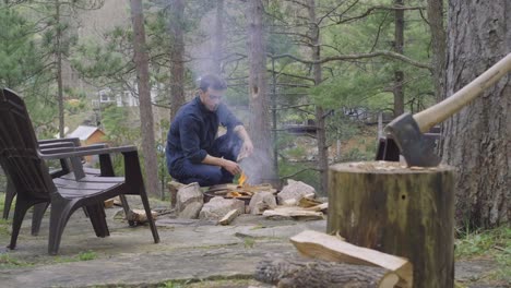 Ein-Mann-Macht-Ein-Feuer-In-Einer-Feuerstelle-Im-Freien,-Umgeben-Von-Bäumen