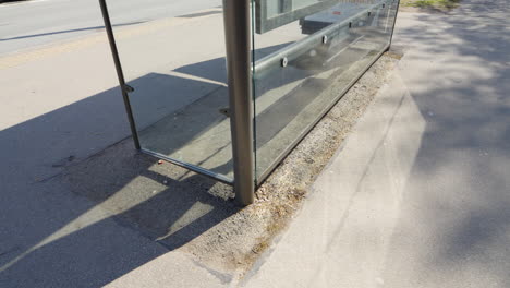 Bus-stop-in-city-with-weathered-asphalt-base-underneath,-motion-view
