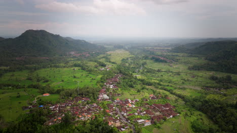 Sidemen-village-emerges-from-jungle-valley-floor-in-Bali,-aerial-establshing