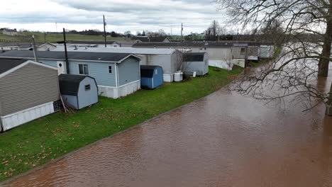 Flooded-riverbed-approaching-manufactured-homes-trailer-park-in-rural-USA