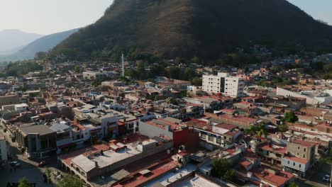 Aerial-360-orbit-overlooking-a-residential-area,-the-city-center-and-the-church-of-Tamazula-de-Gordiano