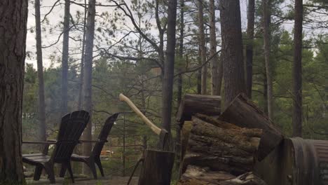 Chopping-wood-area-with-logs,-an-axe,-and-chairs-in-a-forest,-creating-a-rustic-outdoor-scene