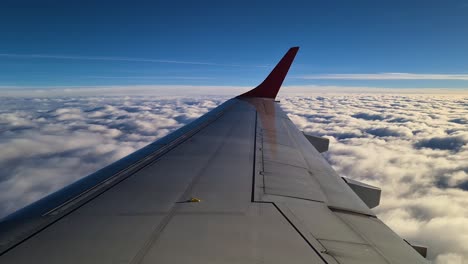 Blick-Auf-Die-Tragfläche-Eines-Flugzeugs-Während-Des-Fluges-über-Dem-Wolkenmeer,-Passagier-POV