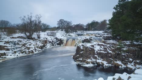 Ein-Zeitraffer-Eines-Schwachen-Wasserfalls-Auf-Dem-Fluss-Tees-In-Teesdale-Unter-Einer-Schneedecke