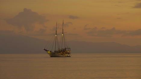 Moored-sailboat-at-sunset-over-sea-during-golden-hour