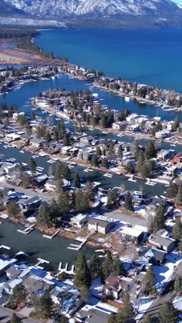 Vertical-Video,-Drone-Shot-of-Tahoe-Keys,-Lake-Tahoe,-California-USA,-Houses,-Canals,-Lakeside-and-Snow-Capped-Hills