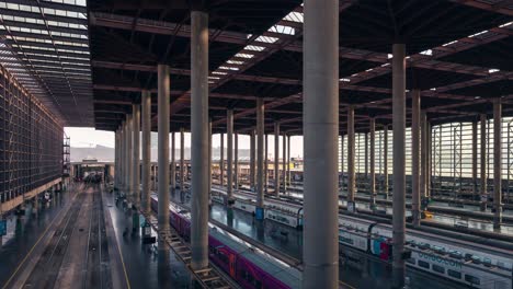 Left-to-right-pan-shot-of-Busy-atocha-railway-station-platforms-in-Madrid-during-sunny-day-high-Speed-trains-on-the-track
