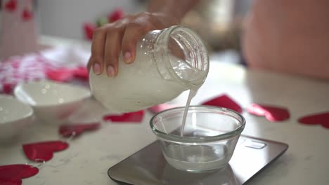 Kokosmilch-In-Eine-Kleine-Schüssel-Auf-Einer-Küchenwaage-Gießen,-Einen-Besonderen-Valentinstagskuchen-Backen,-Veganer-Schokoladenkuchen,-Eifrei,-Pflanzlich,-Milchfrei