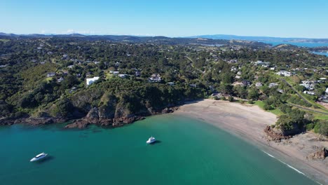 Playa-Oneroa-Con-Barcos-En-La-Isla-Waiheke,-Auckland,-Nueva-Zelanda---Toma-Aérea-Con-Drones