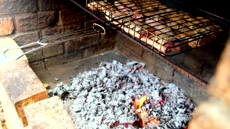 Dripping-chicken-fat-from-grid-on-open-fire-coals-creates-a-flame,-outdoor-grill