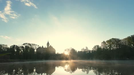Castle-Raduň-in-the-Czech-Republic,-bathed-in-the-warm-glow-of-sunrise-and-mirrored-in-the-still-waters-of-a-serene-pond