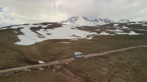 Camper-van-drives-in-mountainous-landscape-of-snowy-mountains