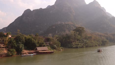 Boot,-Das-In-Der-Nachmittagssonne-Den-Fluss-Hinunter-Schwimmt,-In-Der-Bergstadt-Nong-Khiaw-In-Laos,-Südostasien