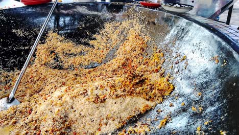 Local-Uzbek-preparing-Uzbek-pilav-or-plov,-a-national-dish-of-Uzbekistan-and-a-rice-dish-common-for-people-of-Central-Asia-in-Samarkand,-Uzbekistan