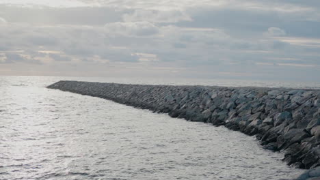 Stony-breakwater-extending-under-a-cloudy-sky-in-Ovar,-Portugal