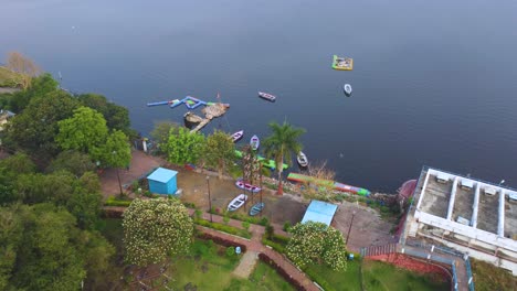 Toma-Aérea-De-Drones-De-Un-Parque-Público-Recreativo-Y-Barcos-Alrededor-Del-Lago-Superior-De-La-Ciudad-Capital-De-Bhopal,-Madhya-Pradesh,-Durante-La-Mañana-En-La-India.