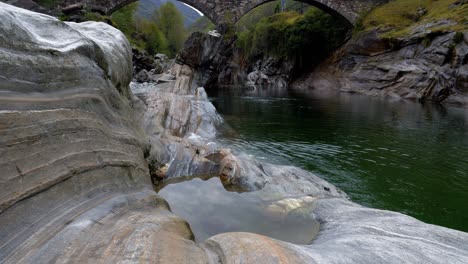 Pan-up-to-Ponte-dei-salti-roman-arched-bridge-crosses-river-in-Lavertezzo-Verzasca-Switzerland