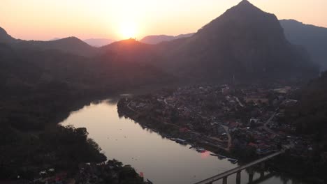 golden-sunset-over-the-bend-in-the-river-with-bridge-in-the-mountain-town-of-Nong-Khiaw-in-Laos,-Southeast-Asia