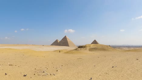 Dunas-Del-Desierto-Con-Grandes-Pirámides-De-Giza-En-La-Distancia-Bajo-El-Cielo-Azul-De-Egipto