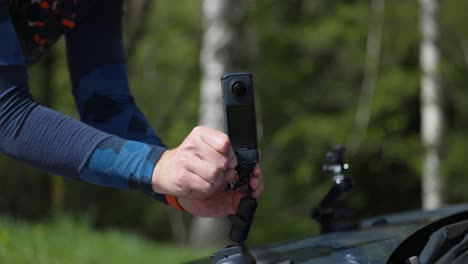 A-Man's-Hands-Securing-the-Insta360-X4-to-the-Hood-of-a-Car---Close-Up