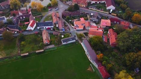 Drohnenansicht-Erfasst-Die-Ansicht-Der-Stadt-Durch-Rückwärtsbewegung-Mit-Häusern,-üppigen-Bäumen,-Straßen,-Fußballplatz