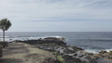 Wide-shot-of-Mosteiros,-Sao-Miguel-coast-with-rough-seas-and-rocky-shoreline-under-a-cloudy-sky,-natural-colors,-daytime