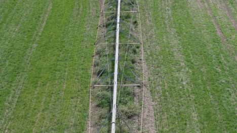 flight-with-a-drone-with-overhead-view-in-a-crop-field-visualizing-a-large-mobile-sprinkler-irrigation-structure-we-appreciate-its-metal-formation-its-wheels-have-not-moved-for-a-long-time