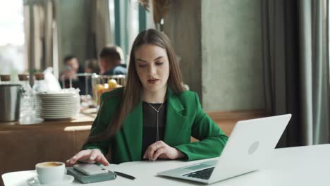 young-professional-Caucasian-woman-is-working-on-her-laptop-in-a-café-but-is-constantly-annoyed-and-distracted-by-her-smartphone