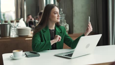 young-professional-Caucasian-woman-with-a-smartphone-is-having-a-video-call-in-a-business-restaurant