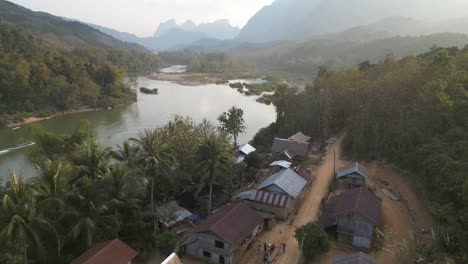 drone-shot-of-dirt-road-leading-through-remote-village-in-the-mountain-town-of-Nong-Khiaw-in-Laos,-Southeast-Asia