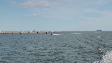Boston-Harbour-Blick-Auf-Die-Stadtlandschaft-Von-Einer-Fähre-Aus,-An-Der-Ein-Motorboot-Entlangfährt