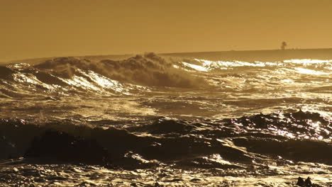 Rough-Sea-Waves-Crashing-On-Rocky-Shoreline-During-Golden-Sunset---Wide-Static-Shot