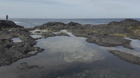 Mosteiros,-Sao-Miguel-Schwarzer-Sandstrand-Mit-Ruhigen-Gezeitentümpeln,-Klippen-Im-Hintergrund