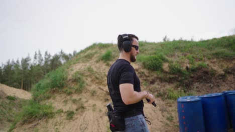 Bearded-masculine-male-walk-and-insert-magazine-in-handgun,-fire-shots