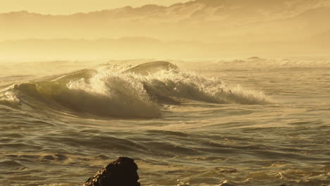 Rough-Sea-Waves-Crashing-On-Rocky-Shoreline-During-Golden-Afternoon---Mid-Pan-Shot