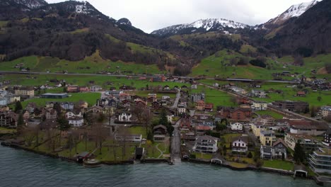 Beckenried-Village-and-Municipality-on-Lake-Lucerne-Under-Swiss-Alps-Hills,-Drone-Shot-on-Cloudy-Day